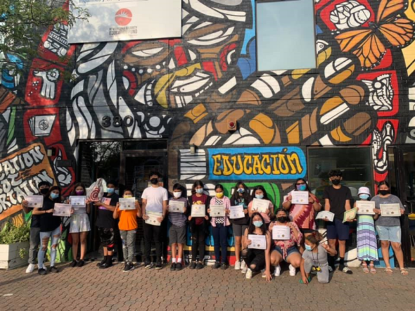 2022 Grantee Tenants and Workers United staff and clients pose with certificates in front of a mural in Fairfax County, VA